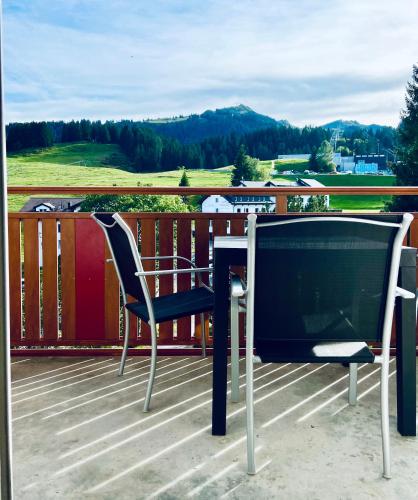 a table and chair on a deck with a television at Haus Alpina - CharmingStay in Flumserberg
