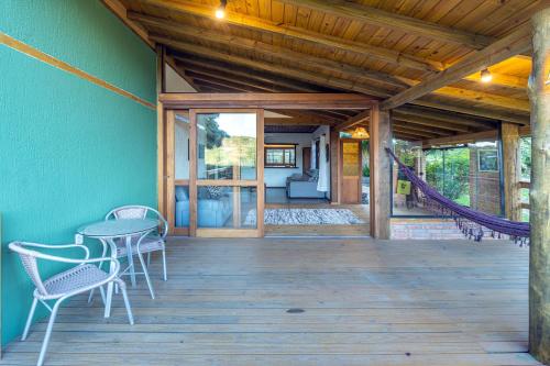 a wooden porch with a table and chairs on it at Pousada Watu Kerere in Praia do Rosa