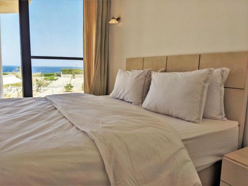 Bett mit weißen Kissen und Meerblick in der Unterkunft Sea & Golf Views 2BR Villa with Free Beach & Pool Access in Hurghada