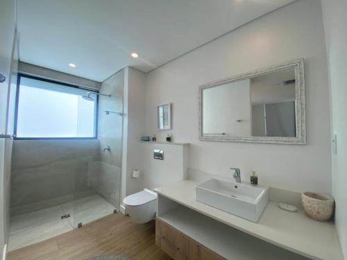 a bathroom with a sink and a toilet and a mirror at Sea La Vie - with Inverter in Umdloti