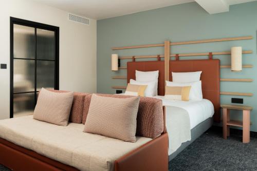 - une chambre avec un lit et un canapé avec des oreillers dans l'établissement Hôtel Parc du Landreau, aux Herbiers