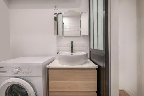 une salle de bain avec un lavabo et une machine à laver dans l'établissement 800m de la plage - 4 adultes et un enfant, au Croisic