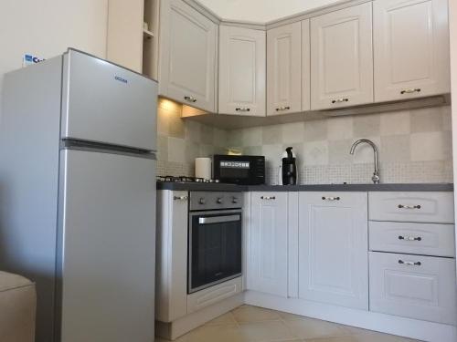 une cuisine avec des armoires blanches et un réfrigérateur dans l'établissement Le castellane, à Castelsardo