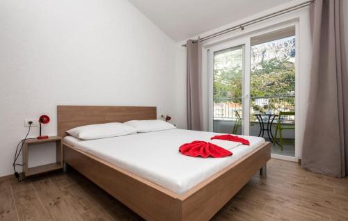 Schlafzimmer mit einem Bett mit weißer Bettwäsche und einem Fenster in der Unterkunft Apartmani Valentina Drvenik in Drvenik