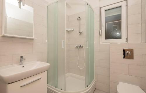 a white bathroom with a shower and a sink at Apartmani Valentina Drvenik in Drvenik