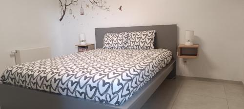 a bedroom with a bed with a black and white comforter at Le Paradis d'Ayli in Aywaille