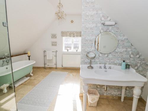 two images of a bathroom with a sink and a tub at Millstone House in Lutterworth
