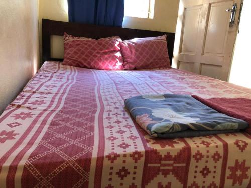 uma cama com um cobertor vermelho e branco em Residencial Meu Tio em Chimoio