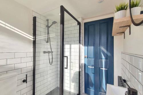 ein Bad mit einer Dusche und einer blauen Tür in der Unterkunft Stunning House, Town Centre Location, Parking 
