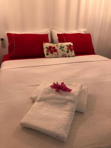 a white bed with towels and red pillows on it at Bangalô Miraflores in Chapada dos Guimarães