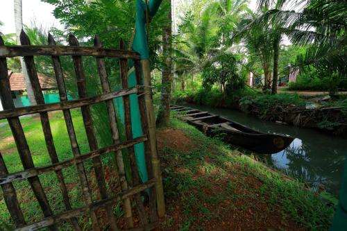 a wooden gate next to a river with a fence at Prakruthi Residency Munroeisland in Munroe Island