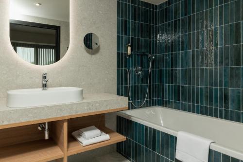 La salle de bains est pourvue d'un lavabo, d'une baignoire et d'un miroir. dans l'établissement Hôtel Parc du Landreau, aux Herbiers