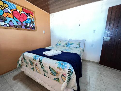 1 dormitorio con 1 cama con una pintura en la pared en Verano House BF, en Baía Formosa