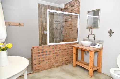 a bathroom with a brick wall next to a sink at Gowan Valley Guest Farm in Balgowan