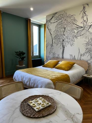 una camera d'albergo con due letti e due tavoli di La Parenthèse Fléchoise, Chambre Armand a La Flèche