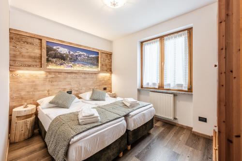 a bedroom with two beds and a window at Villetta Val Di Sole in Commezzadura