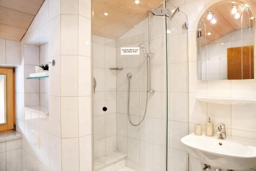 a white bathroom with a shower and a sink at Ferienwohnung Kramernest in Grainau