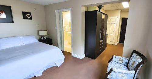 a bedroom with a bed and a chair and a closet at The Medicine Hat Villa in Medicine Hat
