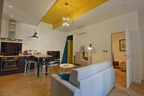 a living room and kitchen with a couch and a table at Le Sensas - Climatisation et Centre in Nîmes