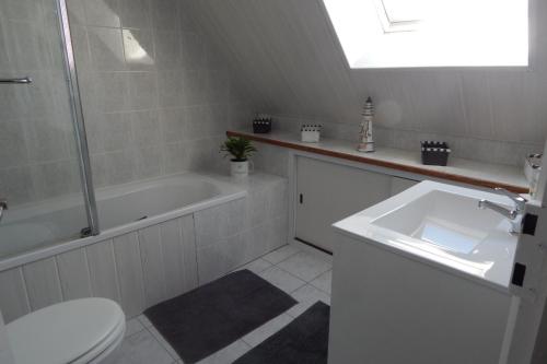 une salle de bain avec un lavabo, une baignoire et des toilettes dans l'établissement La Courtoisie maison de vacances proche plage, à Saint-Malo