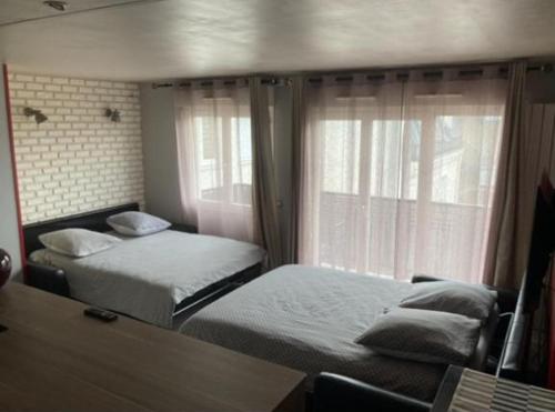 een slaapkamer met 2 bedden en een raam bij Cosy apartment Disneyland Paris en face de la gare RER val d'Europe in Serris