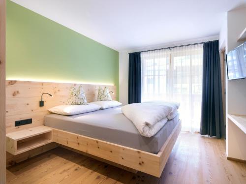 uma cama num quarto com uma grande janela em Altmessnerhof em Dobbiaco