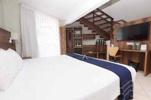 a bedroom with a white bed and a television at Casa Andina Select Zorritos Tumbes in Zorritos