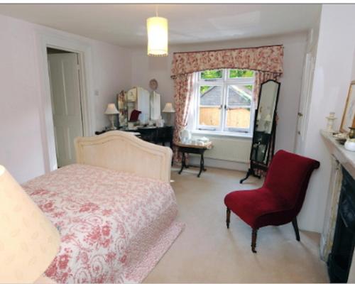 a bedroom with a bed and a chair and a window at Blackbrook House in Holmwood