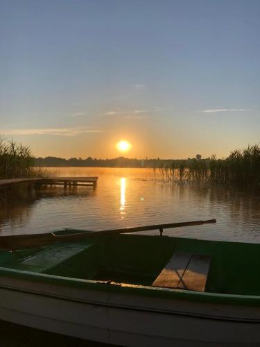 a boat on the water with the sunset in the background at Domek Letniskowy Krejwince in Krejwińce