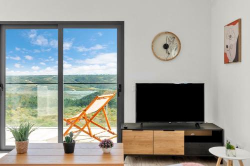 a living room with a tv and a large window at Apartamento Campo e praia in Aljezur
