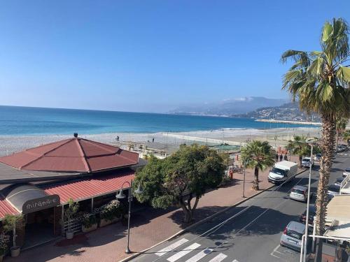 a view of a beach with a building and palm trees at Casa Vale fronte mare in Ventimiglia