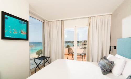 a hotel room with a bed and a large window at Hotel Tahiti in Es Pujols