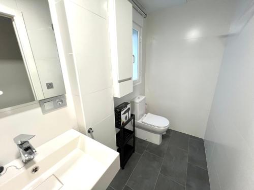 uma casa de banho branca com um lavatório e um WC em APARTMENT EL LLANO em Lucena