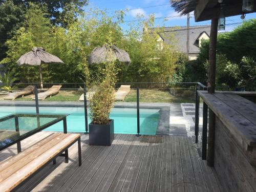 une terrasse en bois avec un banc et une piscine dans l'établissement Les logis du forgeron, Gites de groupe entre Loire & vignes, à Saint-Jean-des-Mauvrets