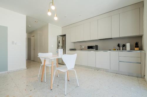 a kitchen with white cabinets and a table and chairs at La Moderna by Wynwood House in Panama City