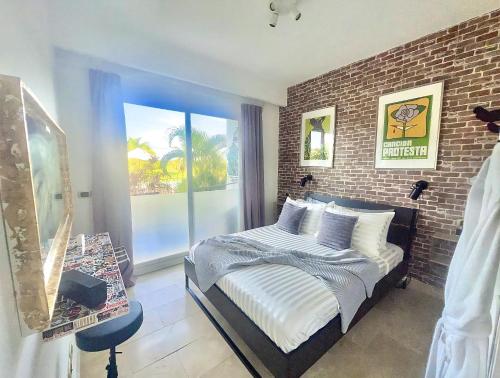 1 dormitorio con cama y pared de ladrillo en Cana Rock Condos Rock & Roll Theme & Golf Course View - infinity Pool en Punta Cana