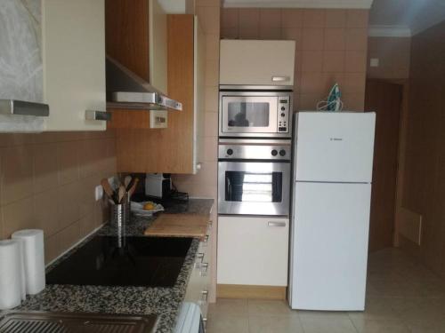 a kitchen with a white refrigerator and a microwave at Apartamento da Aldeia in Montijo