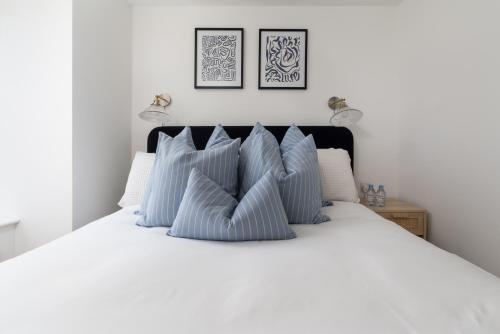 a bedroom with a white bed with blue pillows at Après Beach Apartment Sleeps 4 Penzance in Penzance