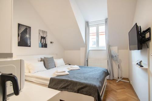 um pequeno quarto branco com uma cama e uma televisão em Private Retreat Close to Stations in Praha 3 em Praga