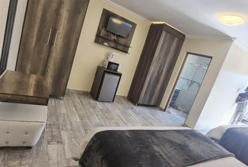 Lasev Resort في بريتوريا: غرفة نوم مع سرير وتلفزيون على الحائط
