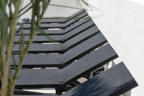 a black bench sitting next to a plant at MAR n MAR CROWN HOTEL-SUITES in Kamari