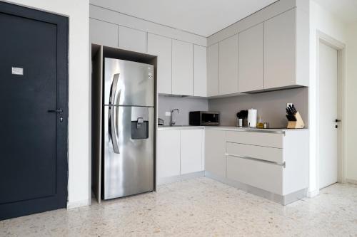 a kitchen with white cabinets and a stainless steel refrigerator at La Moderna by Wynwood House in Panama City