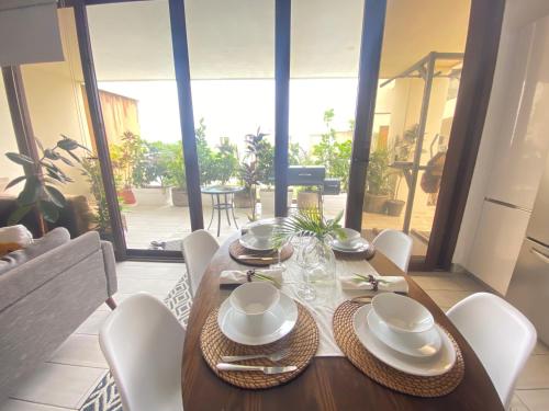 a wooden table with white plates and bowls on it at Hacienda Iguana beach front Penthouse with swimming pools and ocean view in Tola