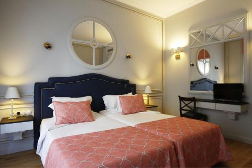 a bedroom with a large bed and a mirror at Grande Hotel do Porto in Porto