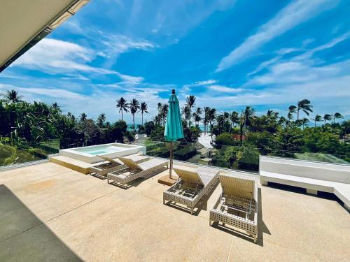 a patio with chairs and an umbrella and a pool at Pina Colada in Amphoe Koh Samui