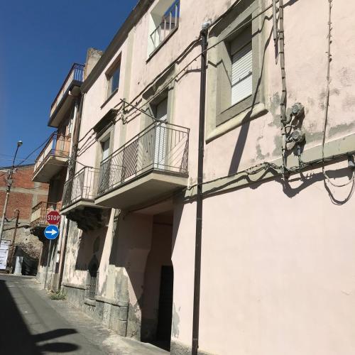a white building with a balcony on a street at Al numero 5 in Francavilla di Sicilia