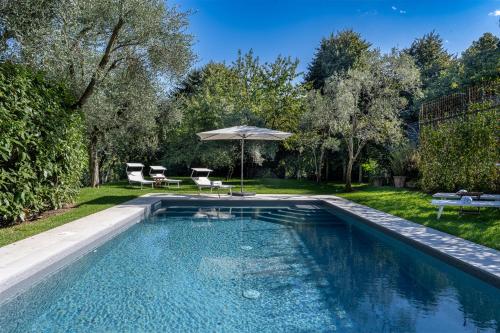 a swimming pool in a yard with an umbrella at Villa Lilla Bellagio - Luxury Pool and Wine with Lake view in Bellagio