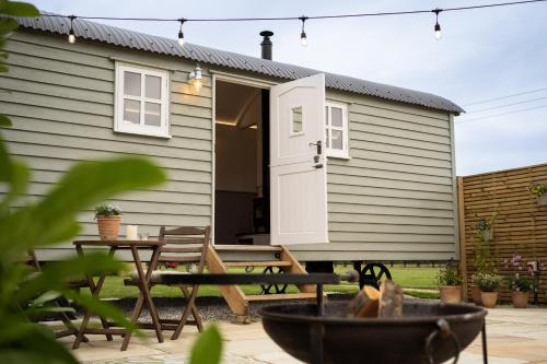 a tiny house with a porch and a patio at The Huts At Woodthorpes in Assington