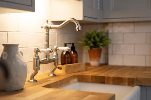 a kitchen sink with a faucet on a counter at The Huts At Woodthorpes in Assington