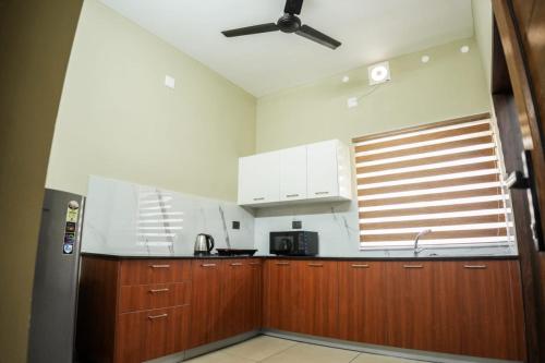 a kitchen with wooden cabinets and a ceiling fan at Zennova Furnished Apartment in Alleppey